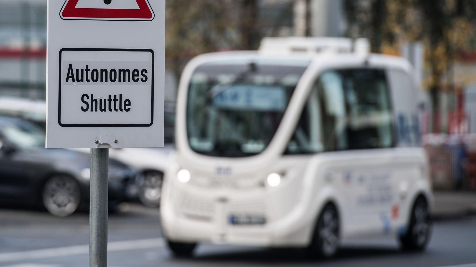 Ein autonomes Shuttle fährt hinter einem Warnschild her, das auf dieses hinweist.