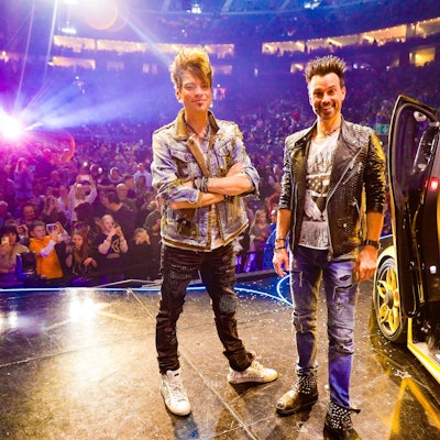 Die Ehrlich Brothers posieren in der Kölner Lanxess-Arena vor einem goldenen Lamborghini.