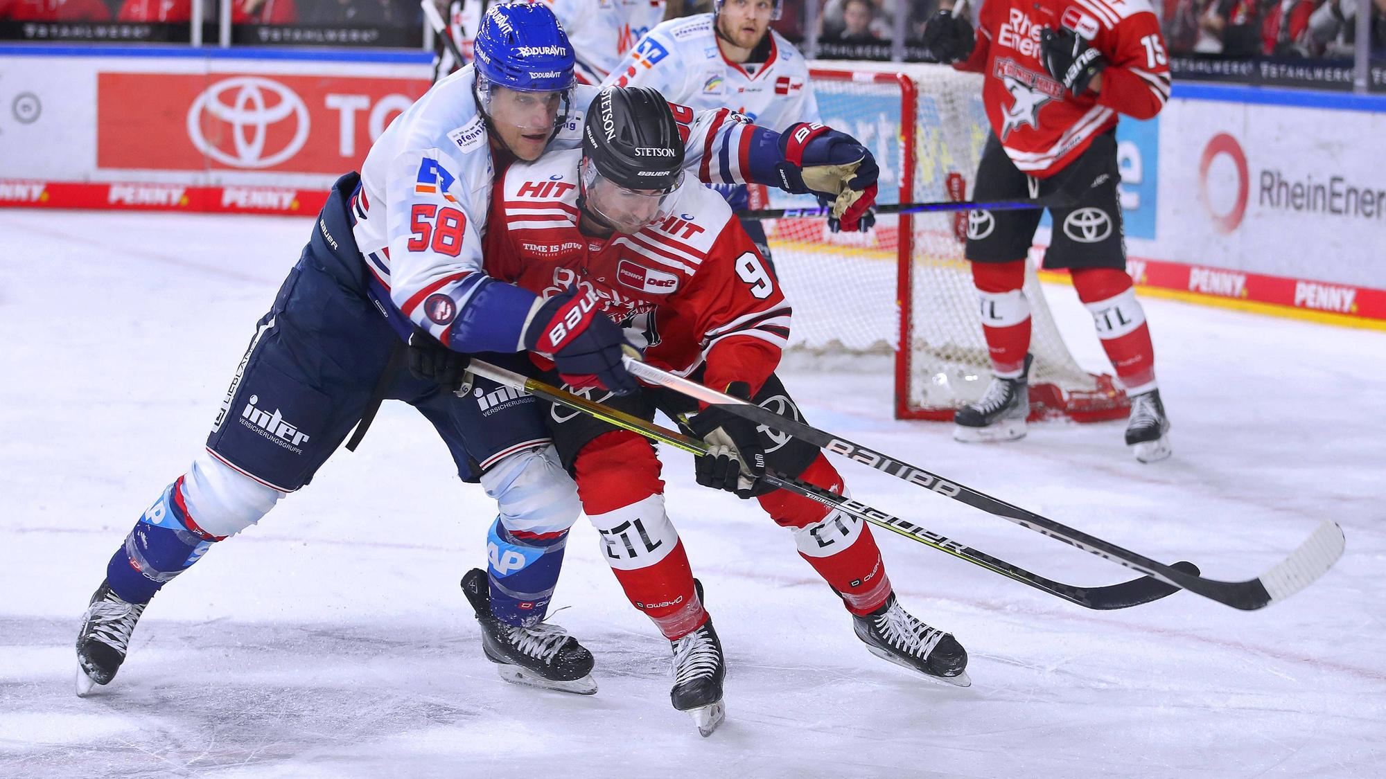 Tyler Gaudet von Adler Mannheim kämpft gegen Kölns Maximilian Kammerer um den Puck.