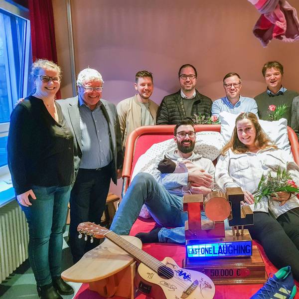 Viele Menschen stehen um das breite und moderne Kreißbett herum, ein Paar liegt drauf.