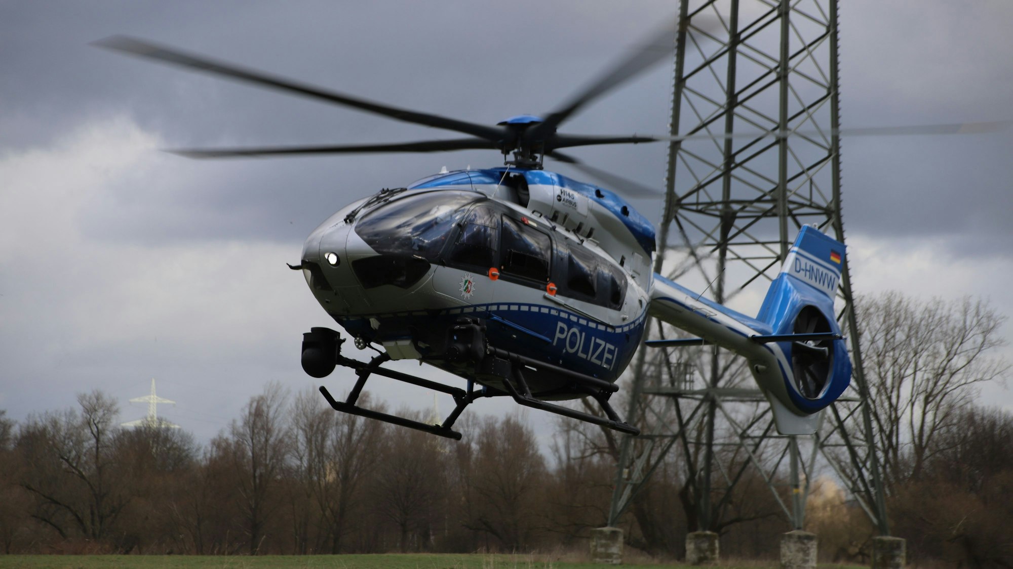 Ein Polizeihubschrauber startet auf einer Wiese.