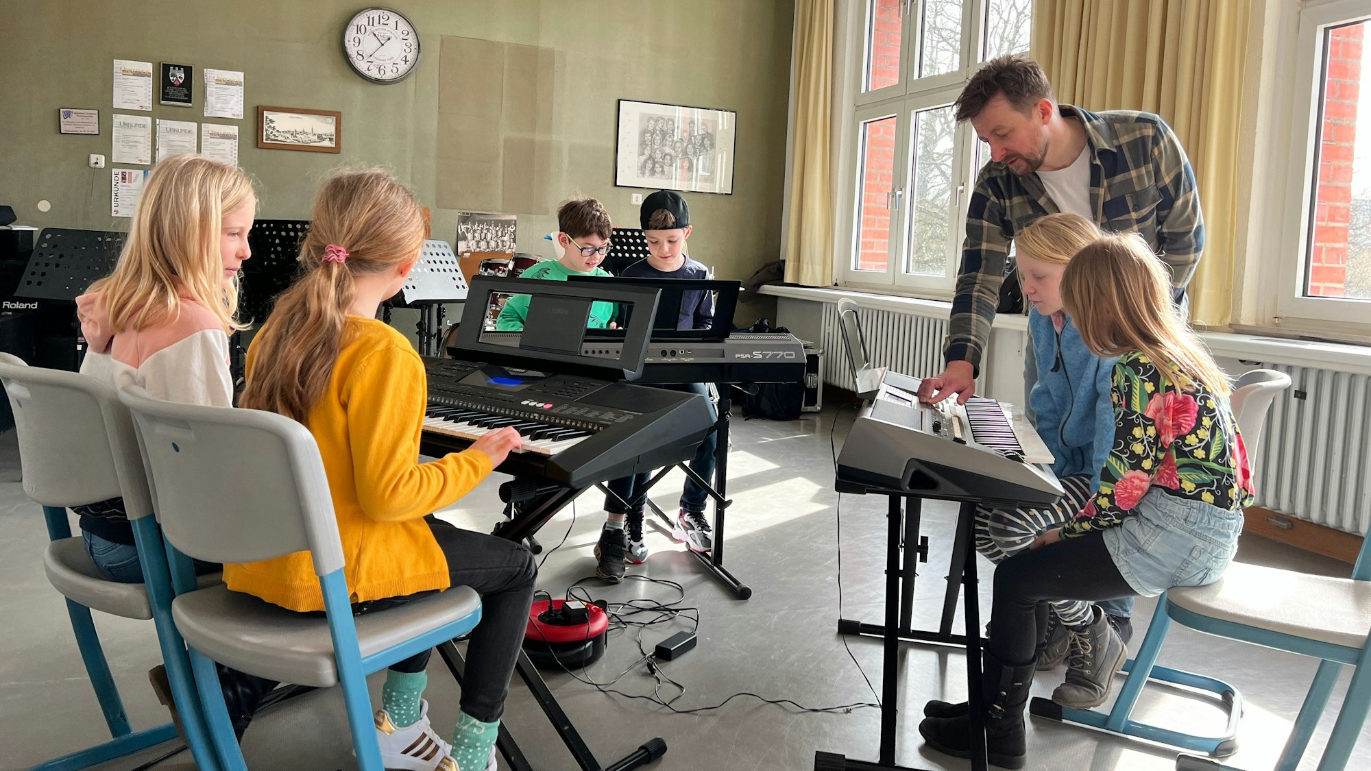 Musiklehrer zeigt Grundschulkindern in der Musikschule Leverkusen, wie Tasteninstrumente bedient werden.