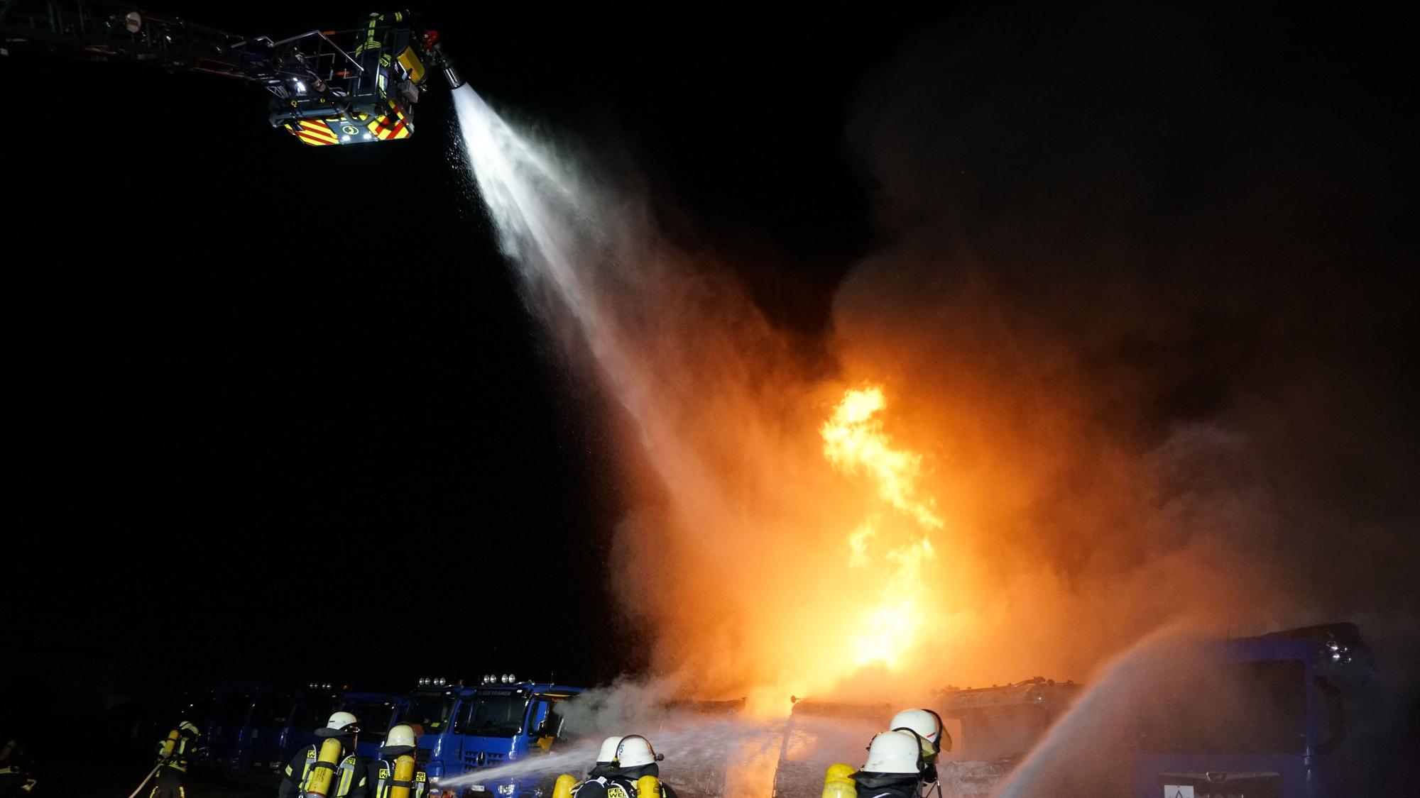 Aus dem Korb der Drehleiter bekämpfen Feuerwehrleute die Flammen .