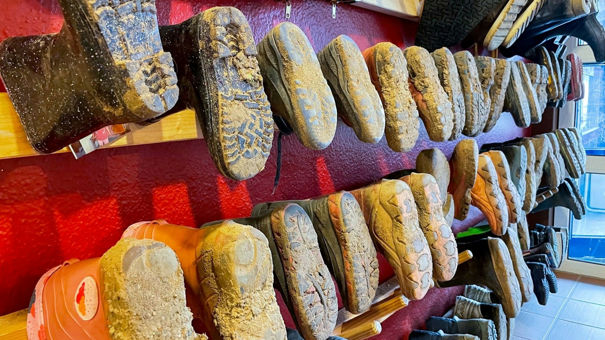 An der Wand hängen Kinderstiefel mit dreckigen Sohlen