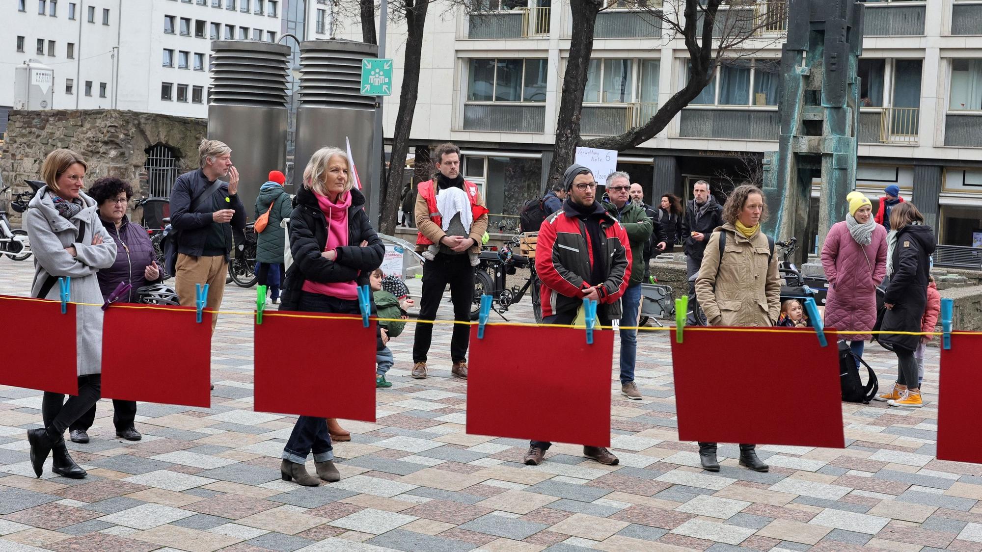 Hinter einer Leine mit Roten Karten stehen Menschen.