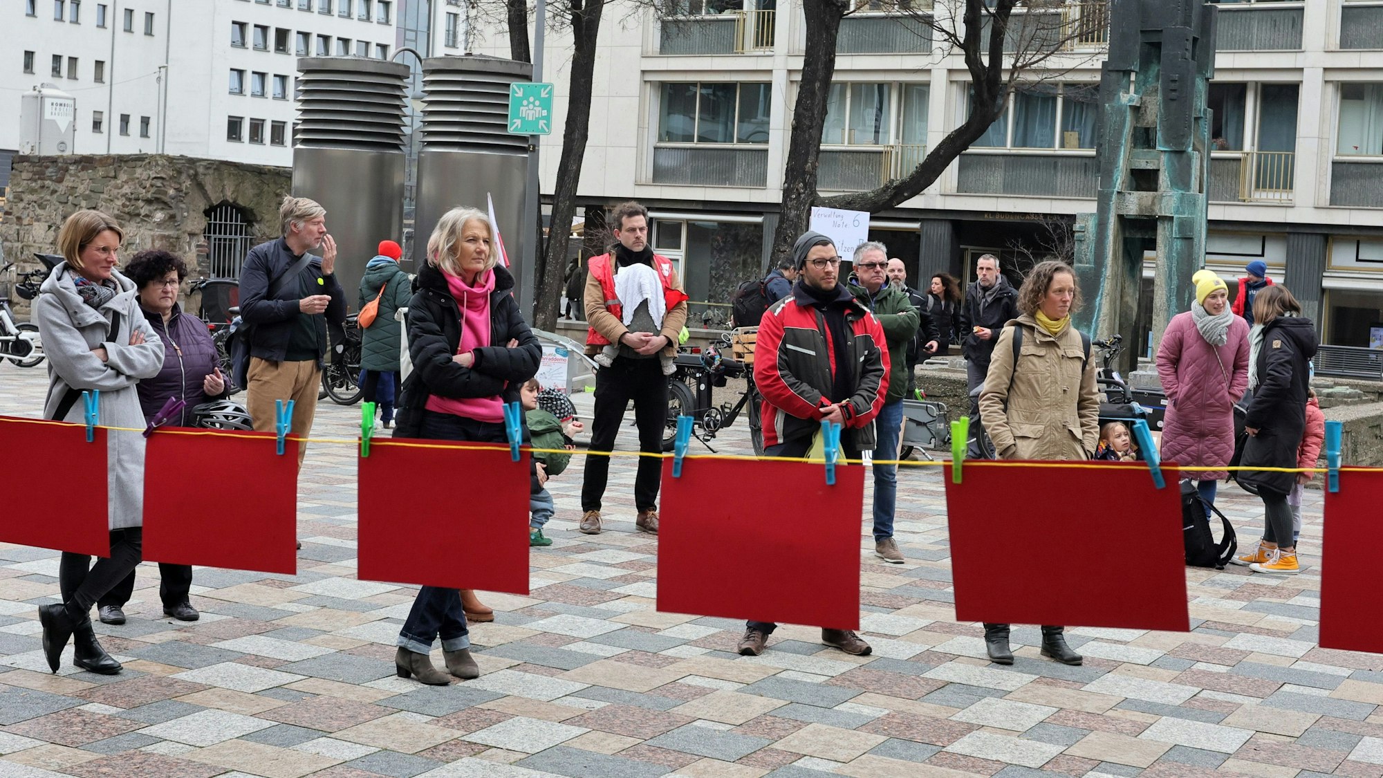 Hinter einer Leine mit Roten Karten stehen Menschen.