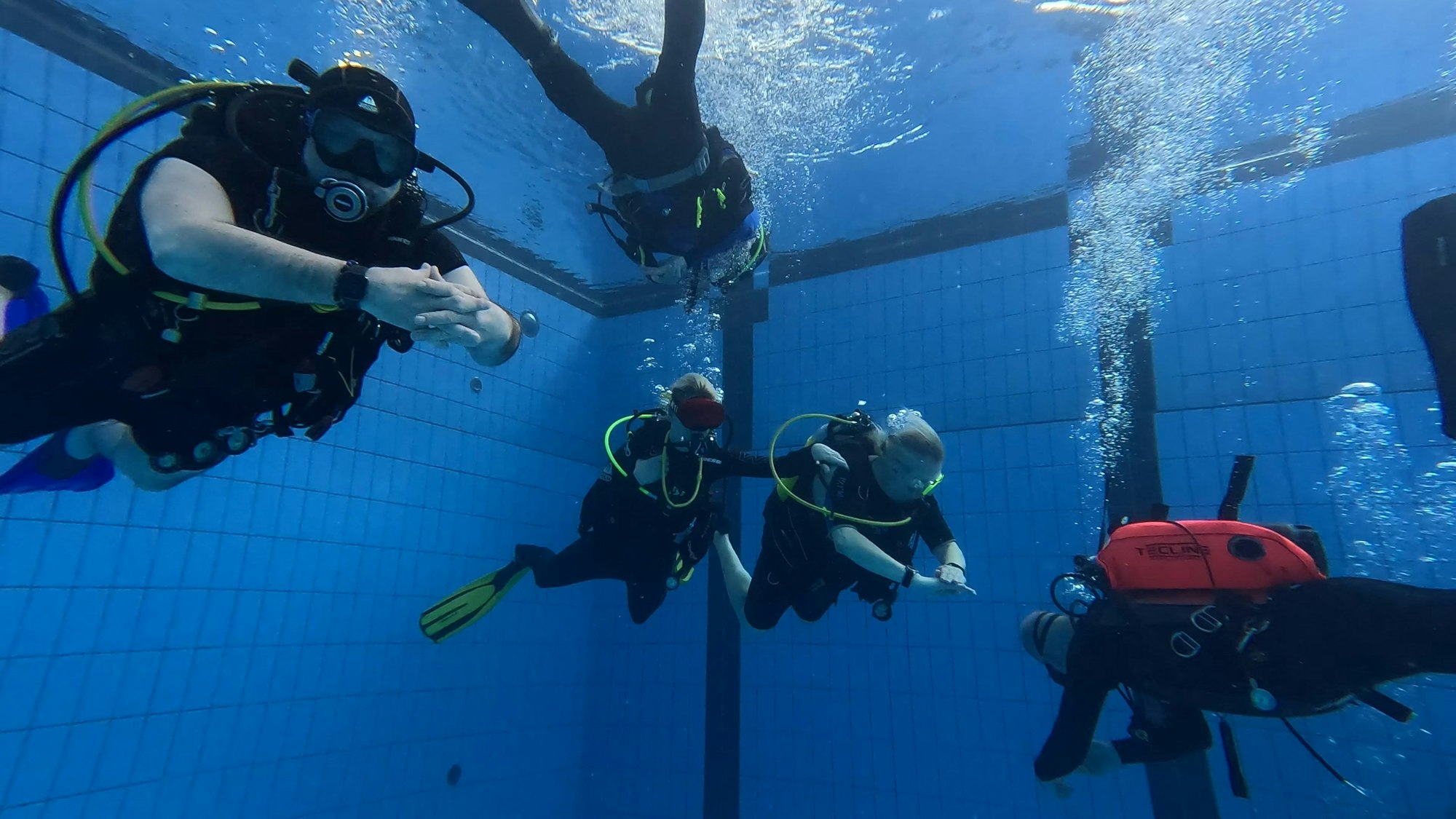 Fünf Taucher unterwasser in einem Becken der Aquarena