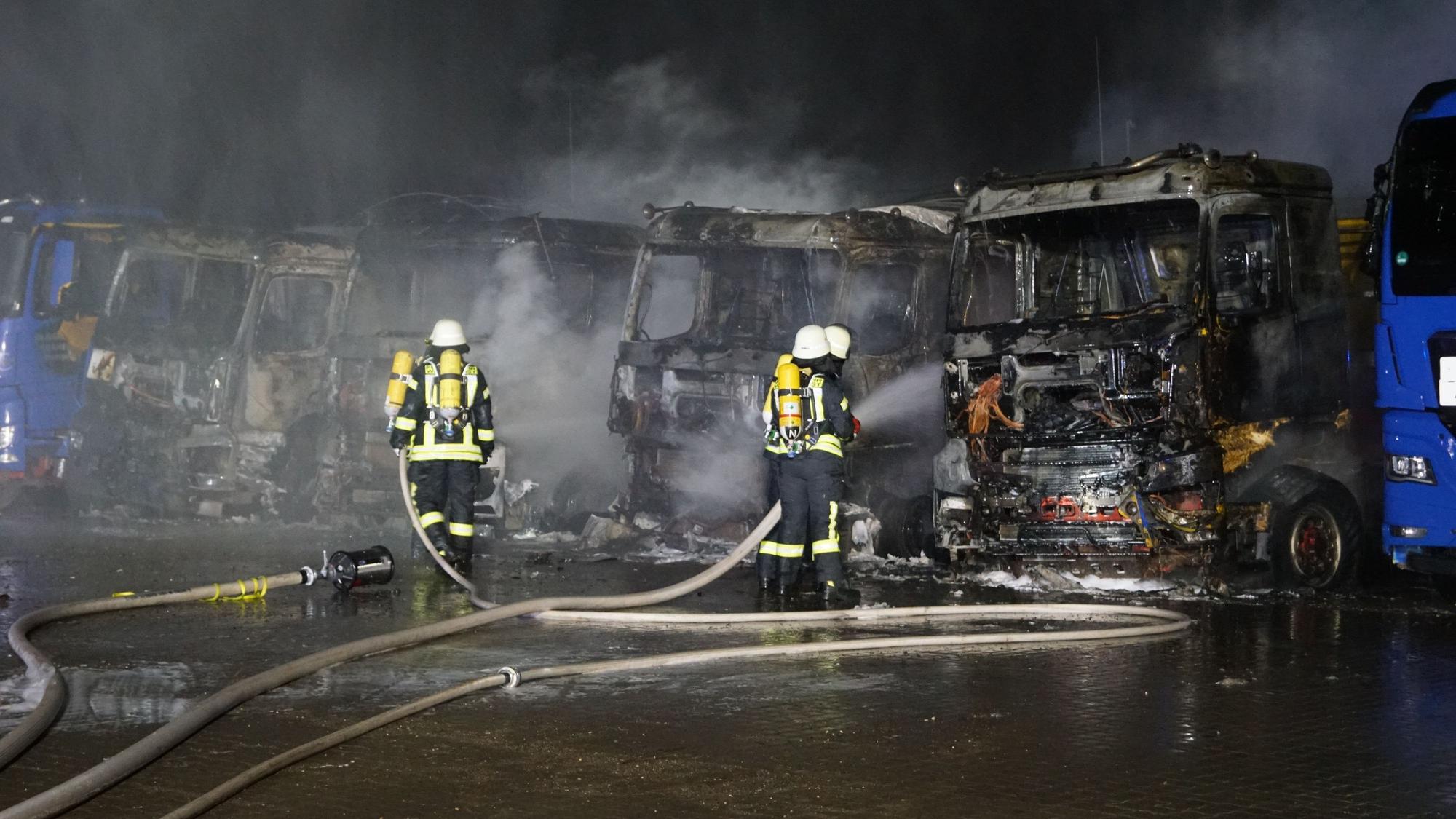 Feuerwehrleute führen Restlöscharbeiten an den zerstörten Lastwagen durch.