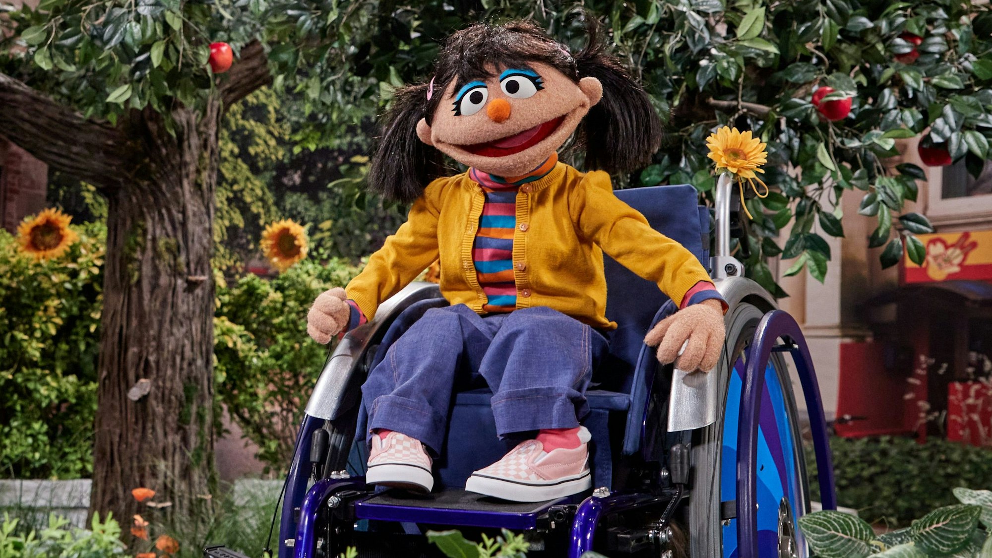 Neuzugang in der „Sesamstraße“: Die Puppe Elin sitzt im Rollstuhl und blickt bei einem Foto-Termin im Fernsehstudio in die Kamera.