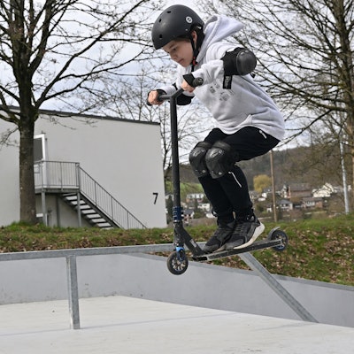 Ein Junge macht Stunts auf seinem Tretroller.