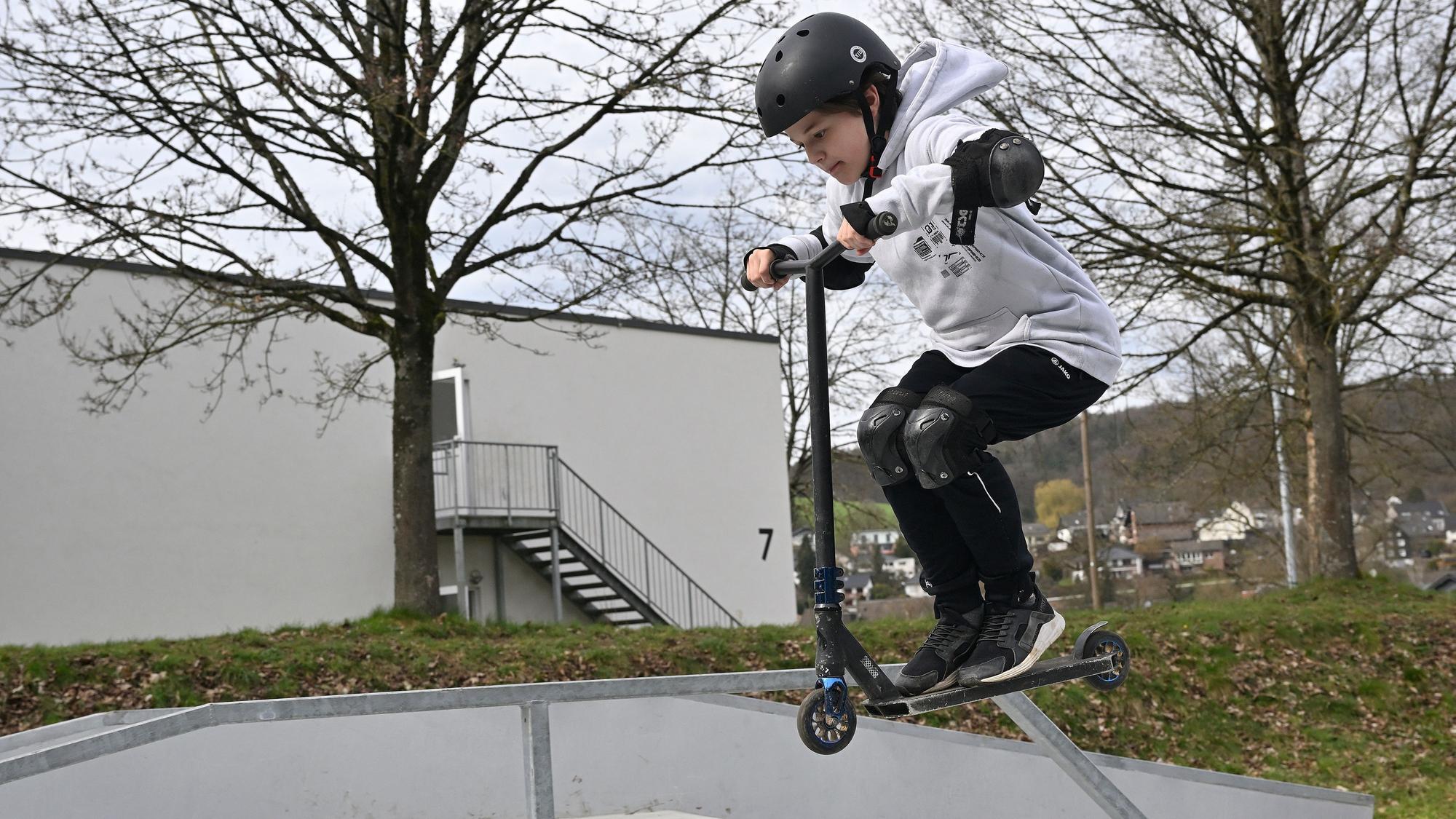Ein Junge macht Stunts auf seinem Tretroller.