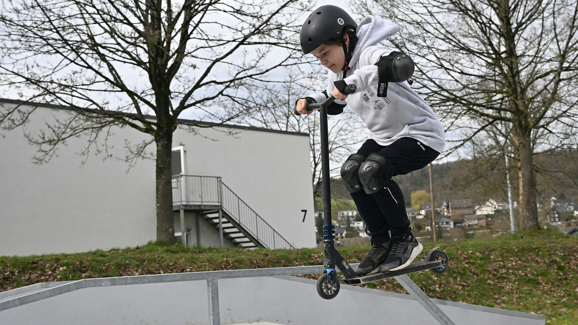 Ein Junge macht Stunts auf seinem Tretroller.