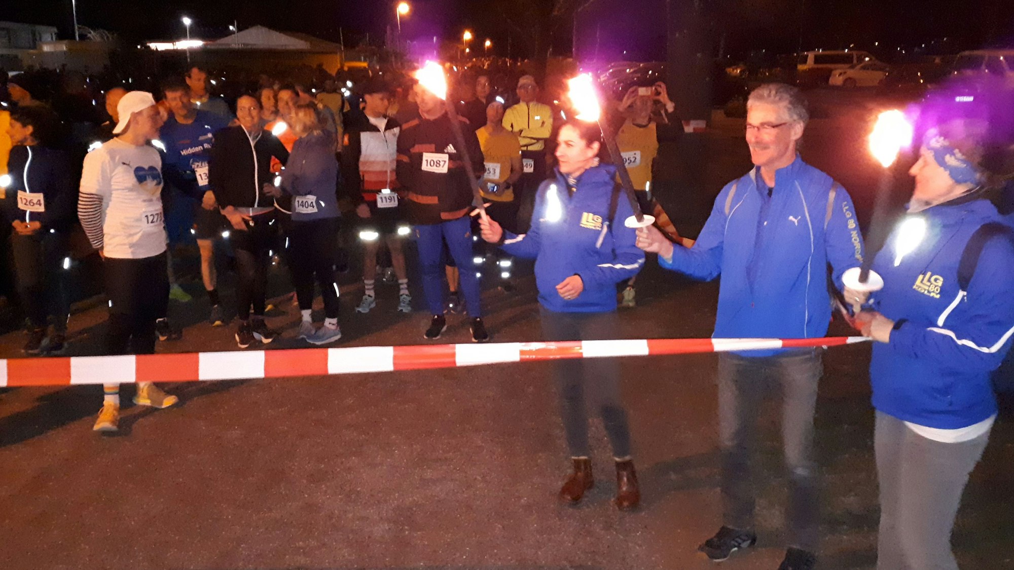 Absperrband als Startlinie, dahinter die Läufer und Helfer