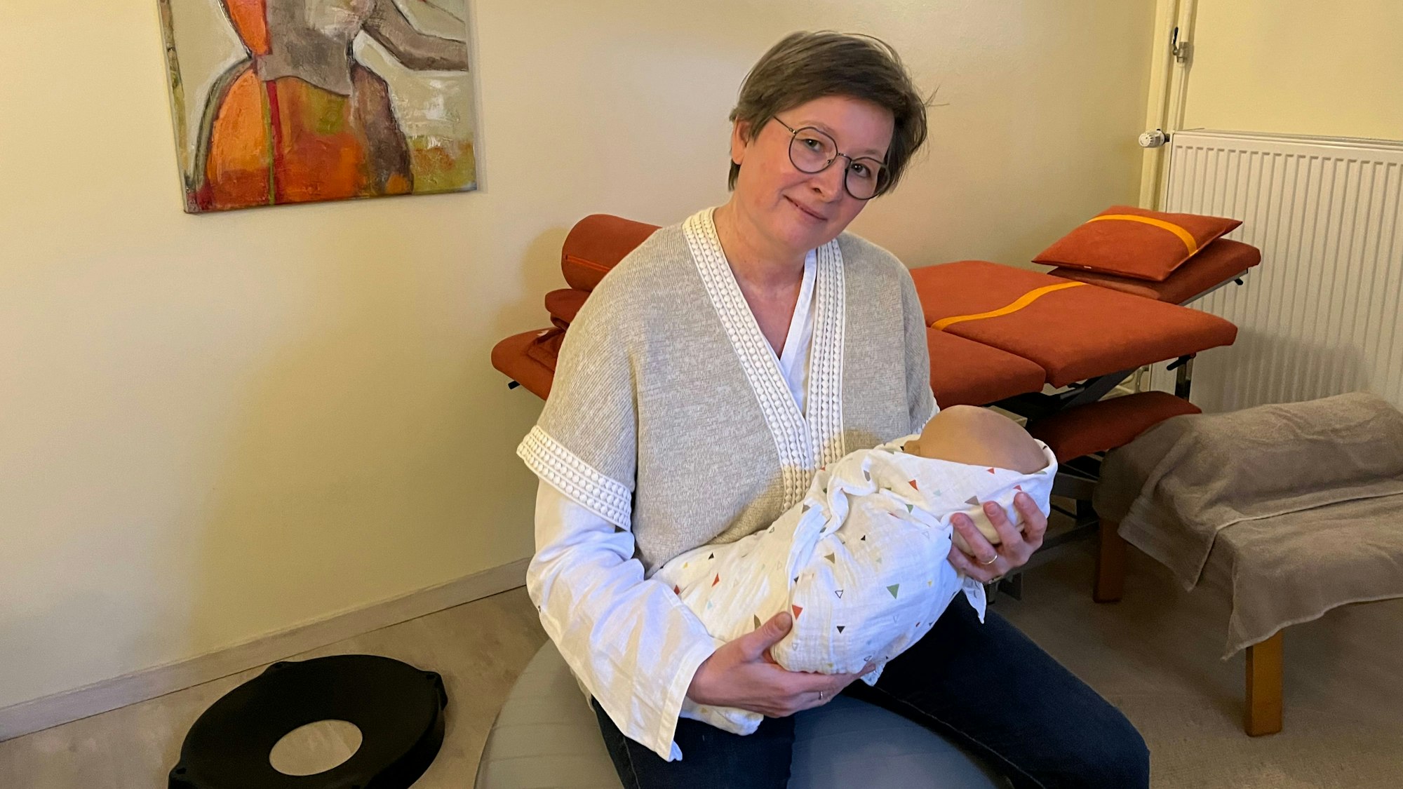 Hebamme Tanja Welling mit einer Babypuppe auf einem Hüpfball