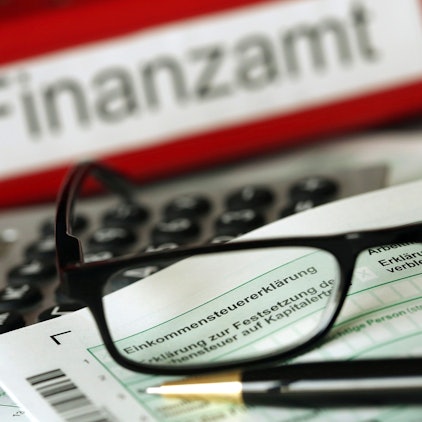 Auf einem Vordruck für die Steuererklärung liegen Stift und eine Brille.+++