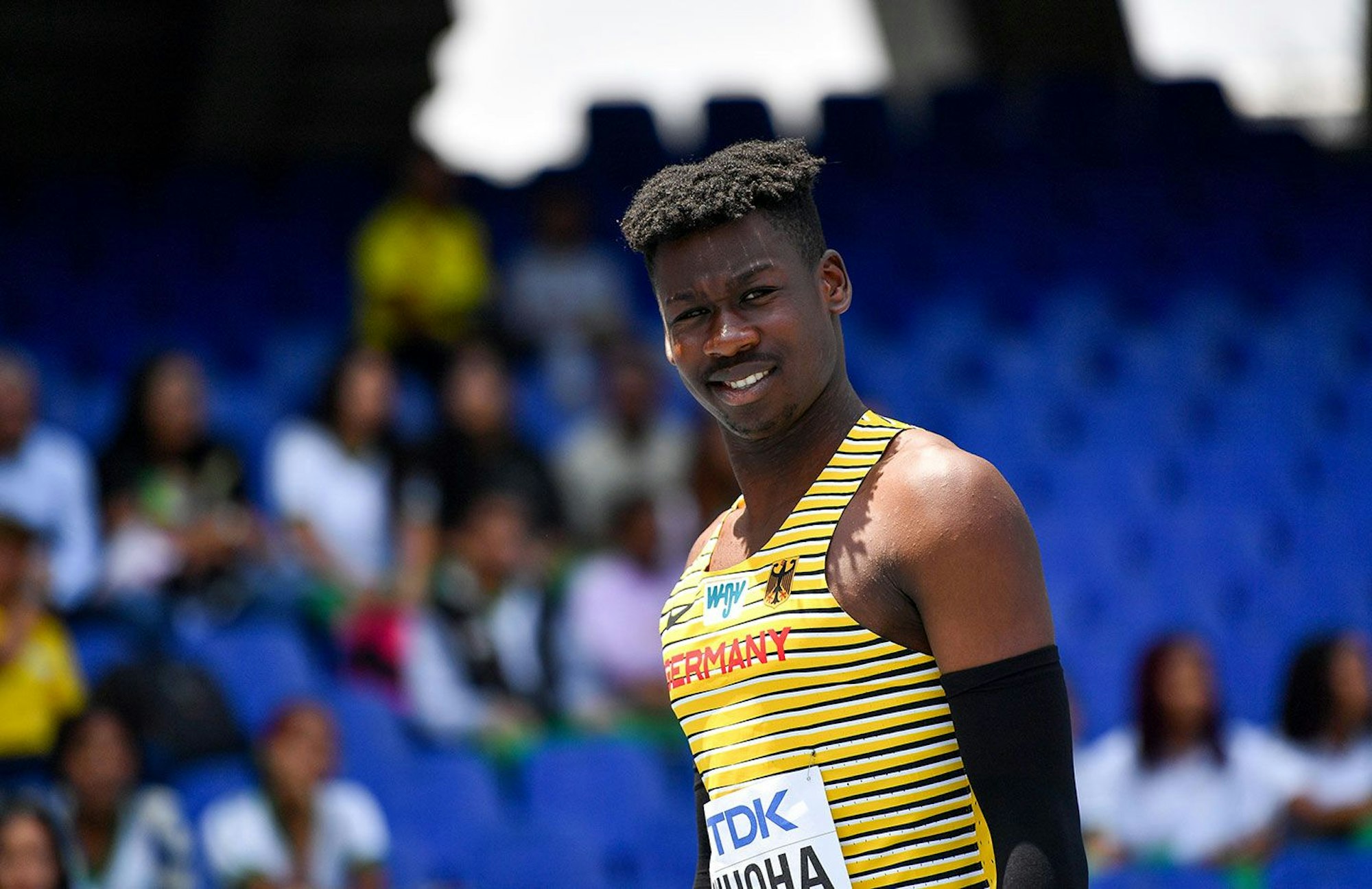 Chidi Onuoha trägt ein gelb-schwarz gestreiftes Deutschlandtrikot und lächelt.
