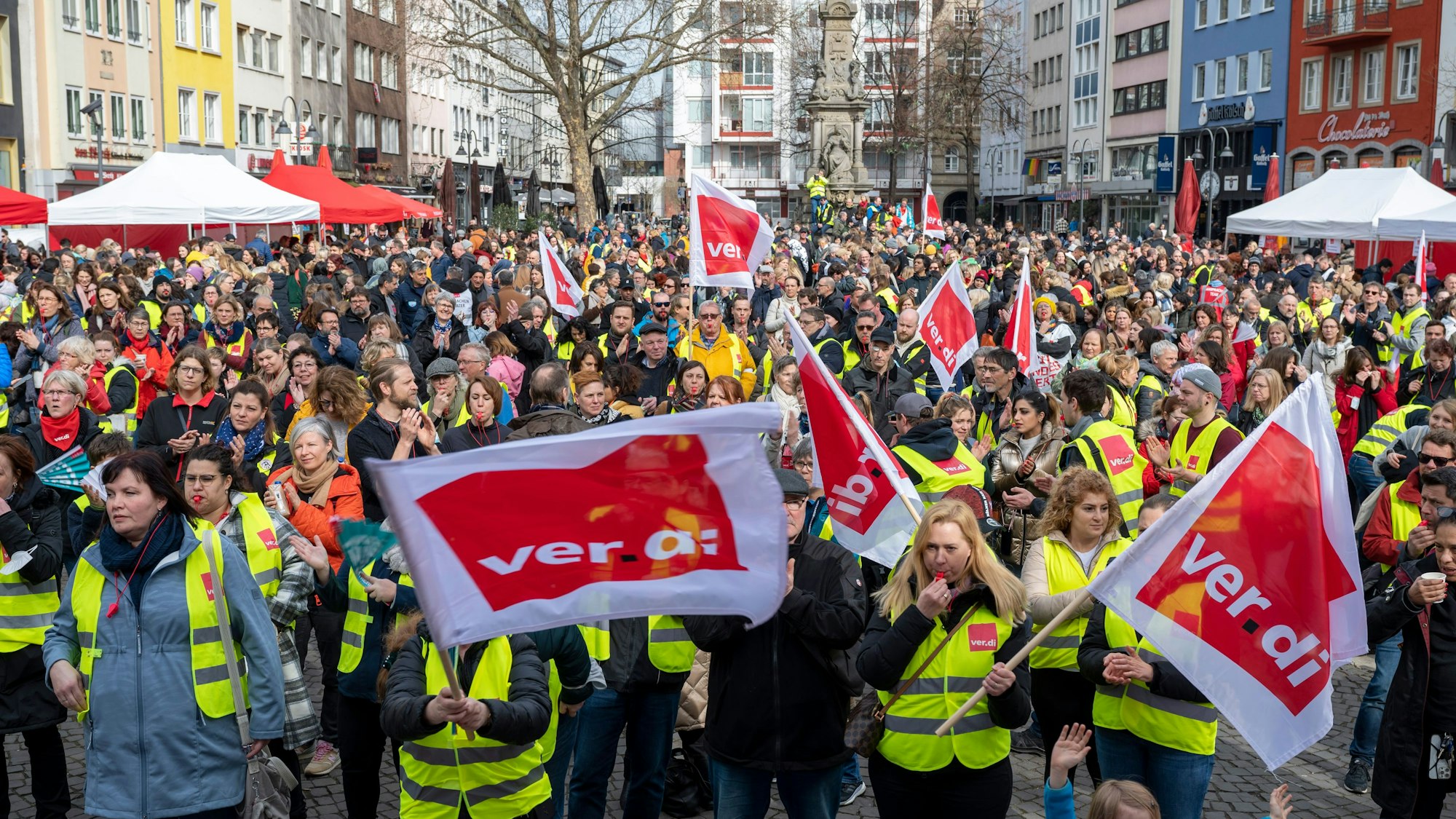 Alter Markt in Köln: Städtische Angestellte demonstrieren vor dem Rathaus. Sie halten große Fahnen der Gewerkschaft Verdi in die Höhe und tragen Warnwesten.