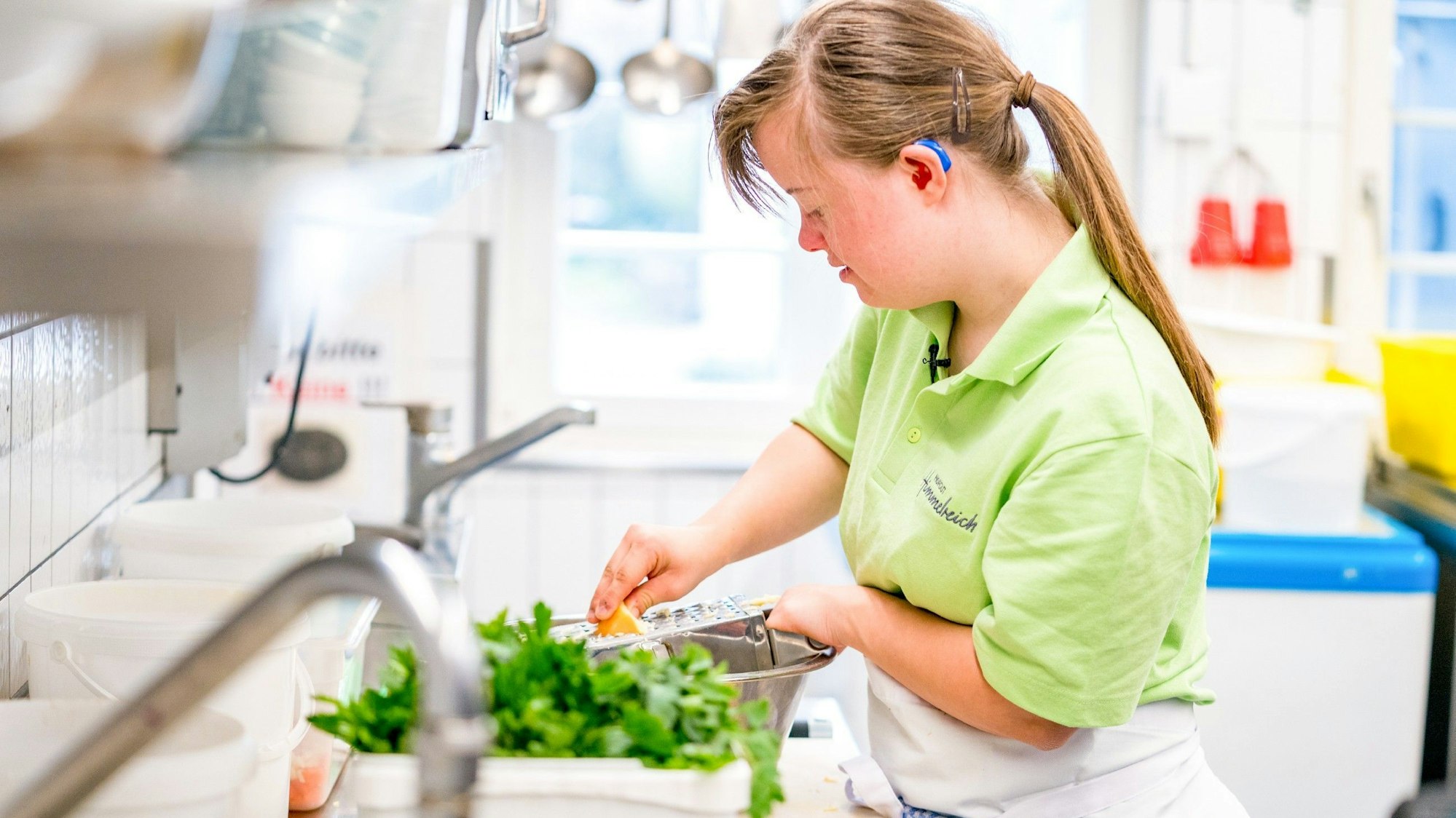 Eine Frau mit Downsyndrom arbeitet in der Küche.