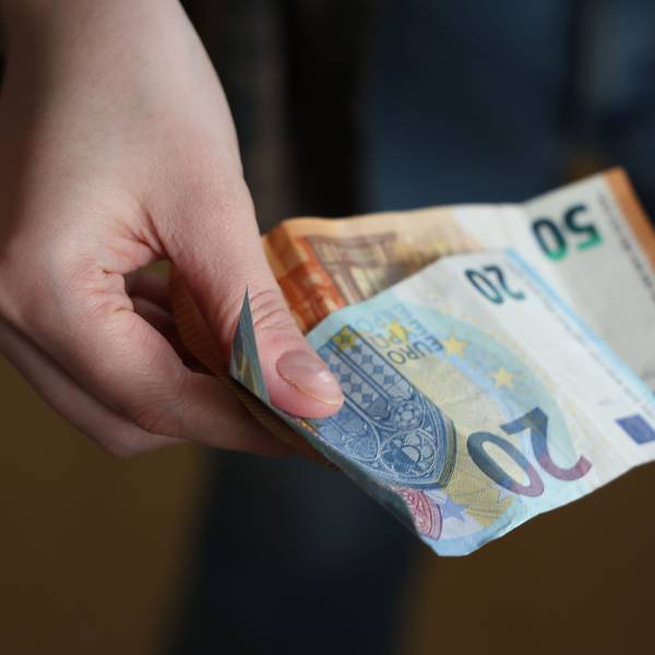 Eine Hand hält einen 20- und einen 50-Euro-Schein
