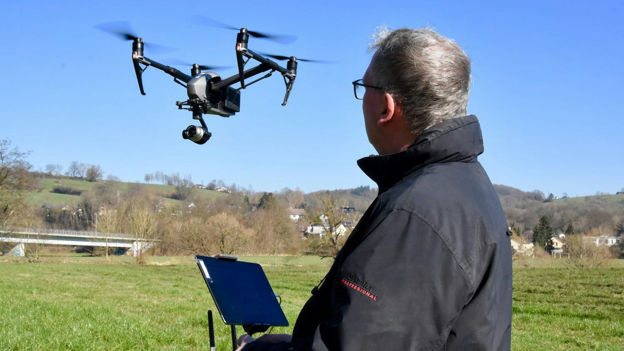 Andreas Müller-Goldkuhle steht auf einem grünen Feld, vor ihm in der Luft fliegt eine Drohne.
