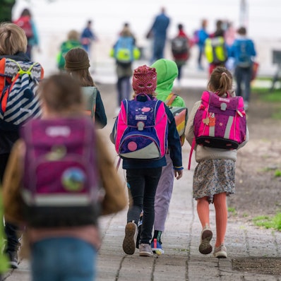 Kinder mit bunten Ranzen auf dem Weg in die Schule.
