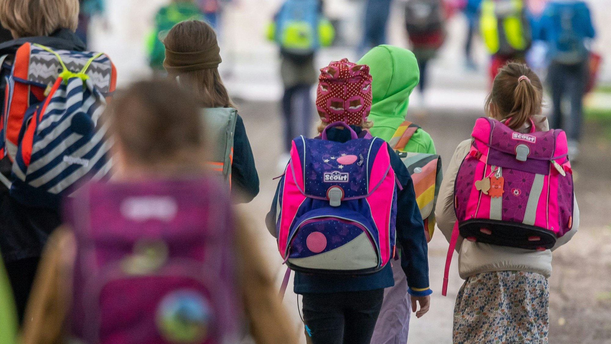 Kinder mit bunten Ranzen auf dem Weg in die Schule.