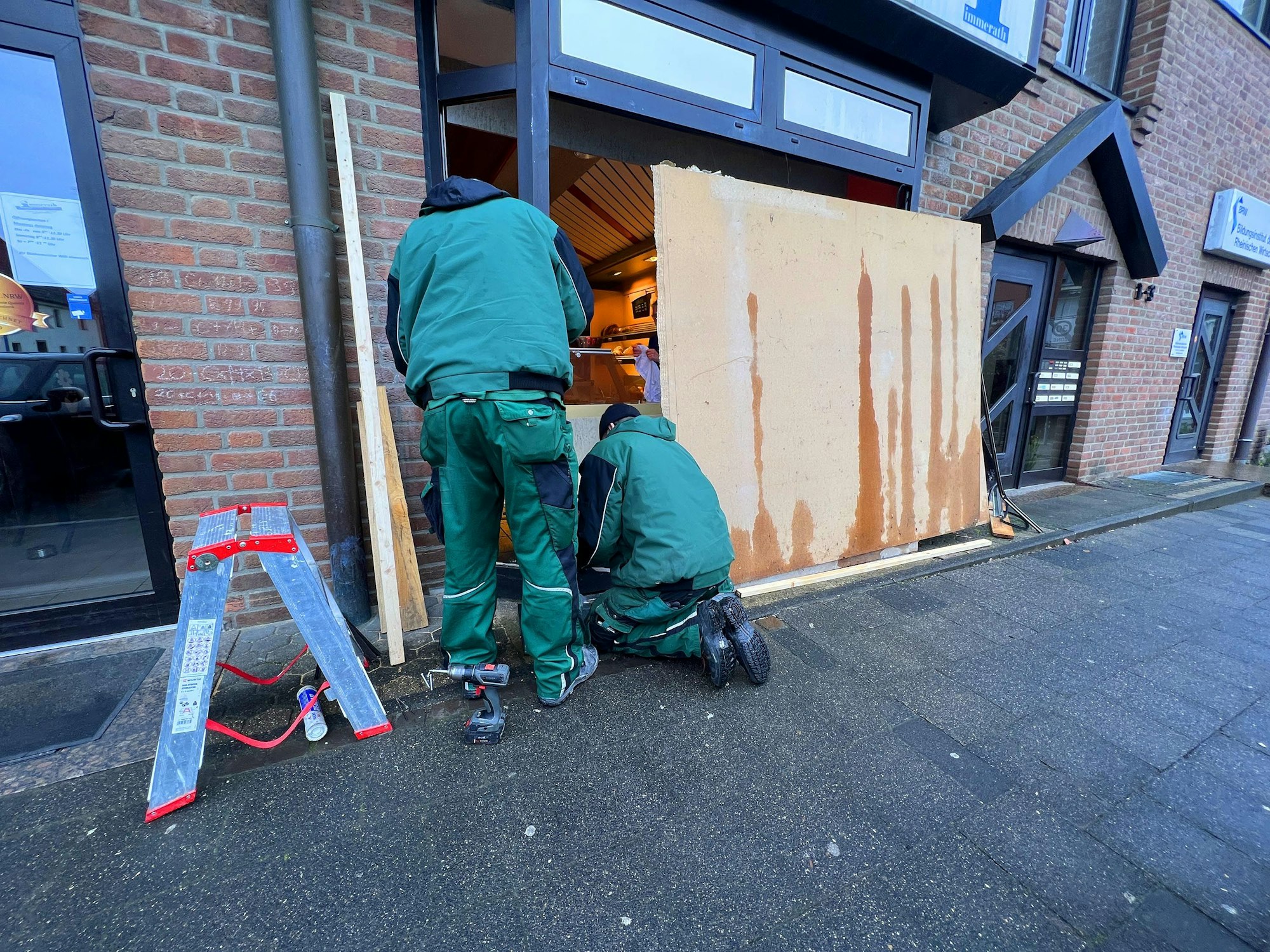 Glaser arbeiten am eingedrückten Schaufenster der Bäckerei.
