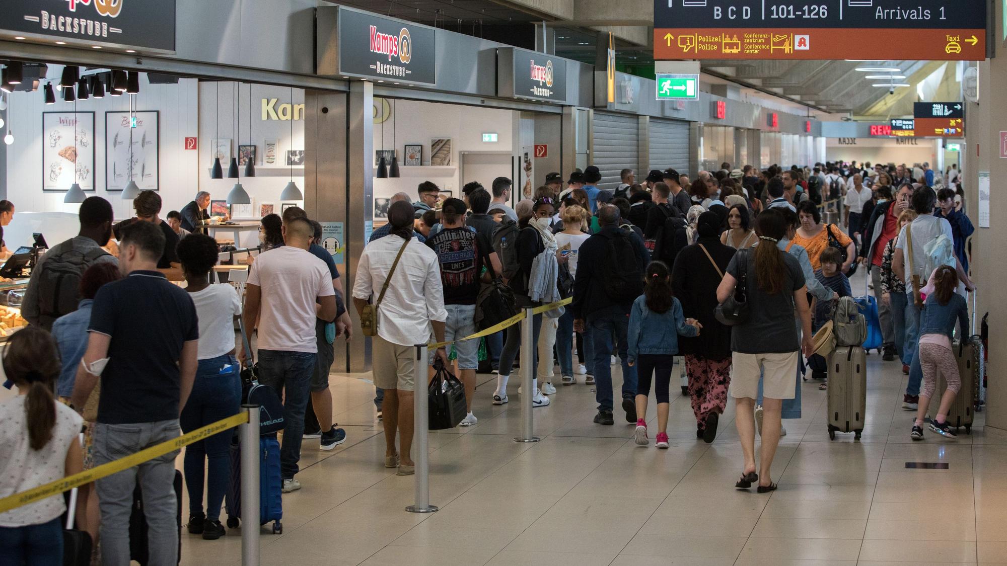 Reisende stehen in den Sommerferien am Flughafen Köln/Bonn in einer Schlange vor der Sicherheitsschleuse.