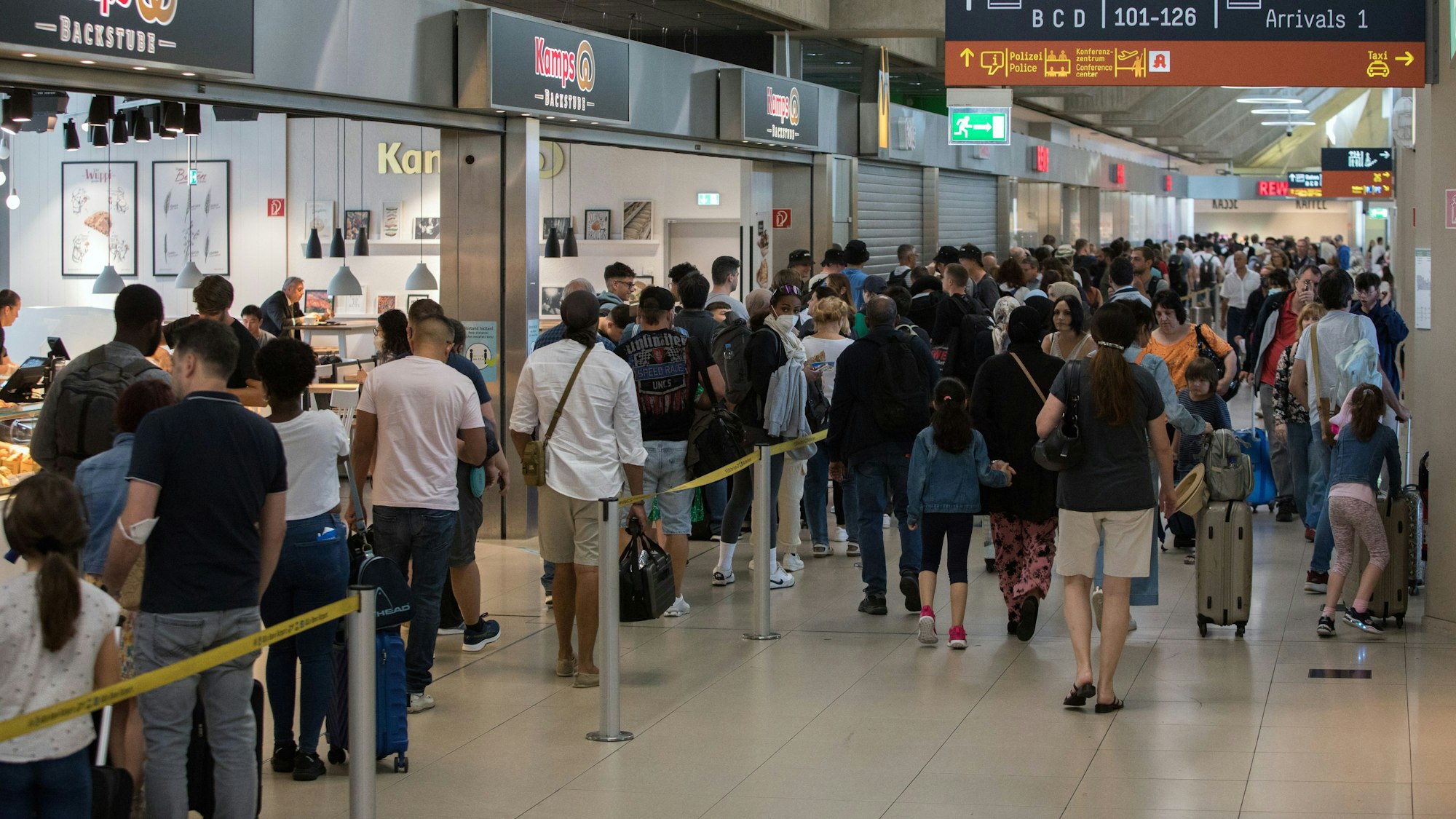 Reisende stehen in den Sommerferien am Flughafen Köln/Bonn in einer Schlange vor der Sicherheitsschleuse.