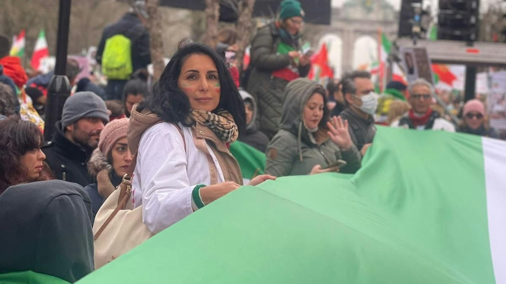 Mitra Nasiri-Sarvi bei einer Demonstration in Deutschland. Sie hält gemeinsam mit anderen Protestierenden eine Iranische Flagge in den Händen.