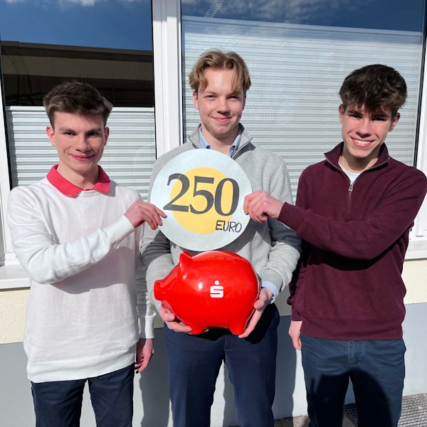 Blick auf drei jungen Männer, die in ihrer Mitte ein Sparschwein halten.