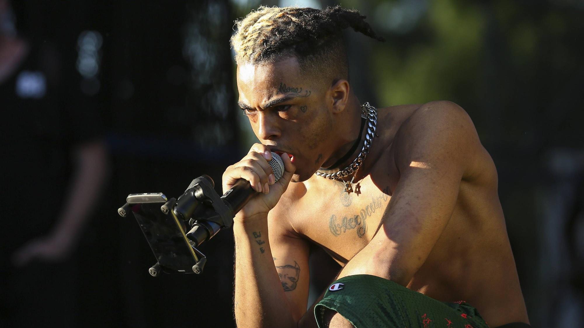 XXXTentacion bei einem Auftritt, oberkörperfrei und mit Mikro in der Hand.