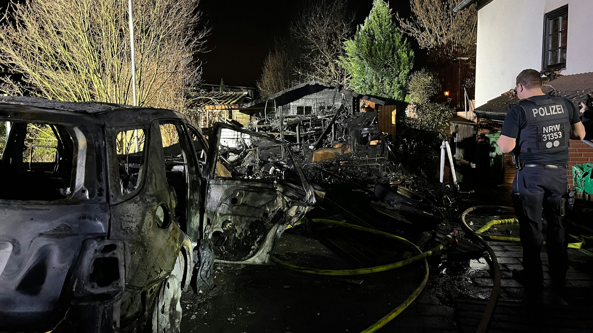 Der Mercedes im Vordergrund und das Gerätehaus im Hintergrund. Ein Polizist steht am Rand.