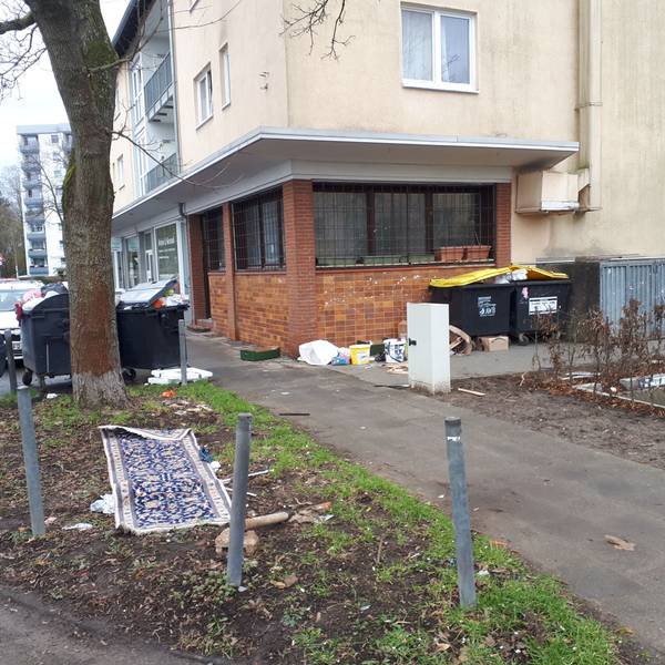 Das Bild zeigt das Haus August-Haas-Straße 1, mit der leerstehenden Gaststätte im Erdgeschoss. In der Umgebung sammelt sich der Müll.