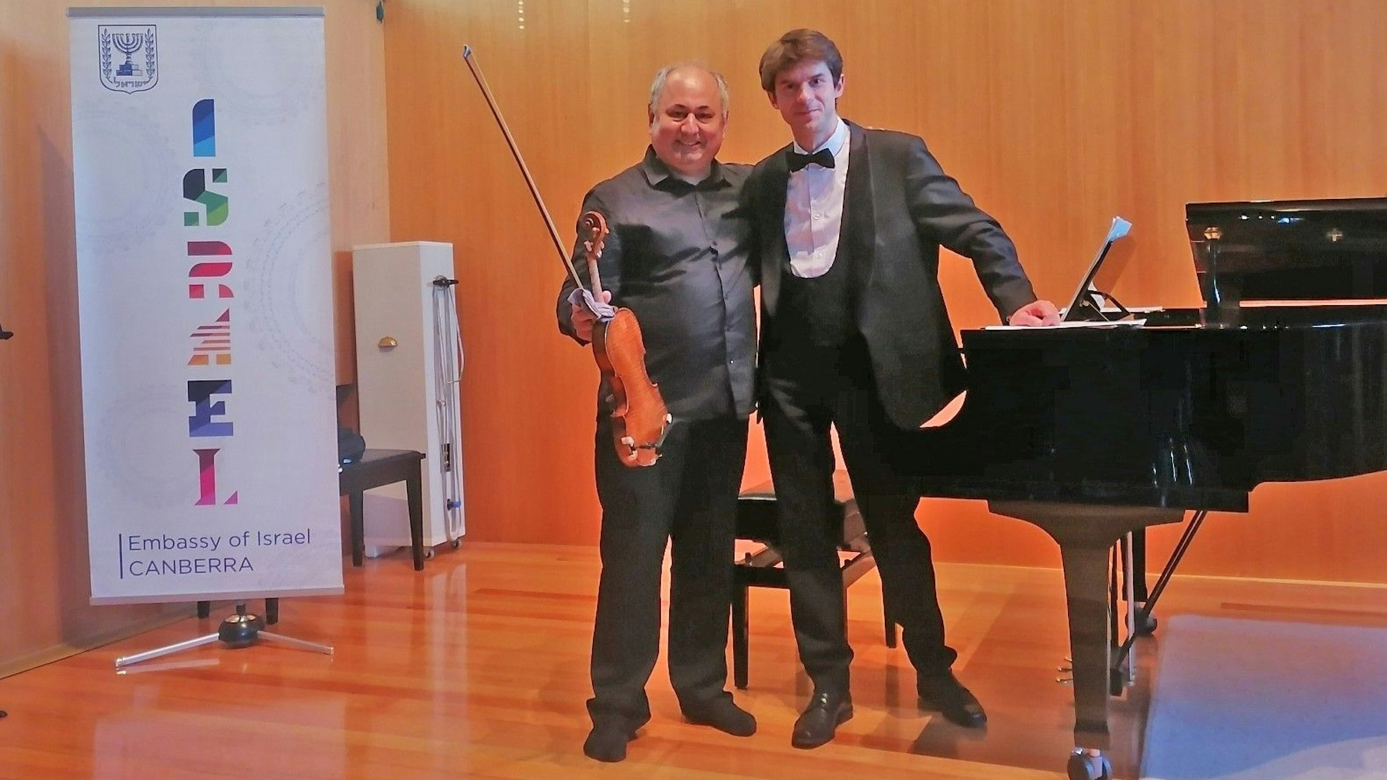 Roman Salyutov steht an einem Flügel, neben ihm ein Geiger.