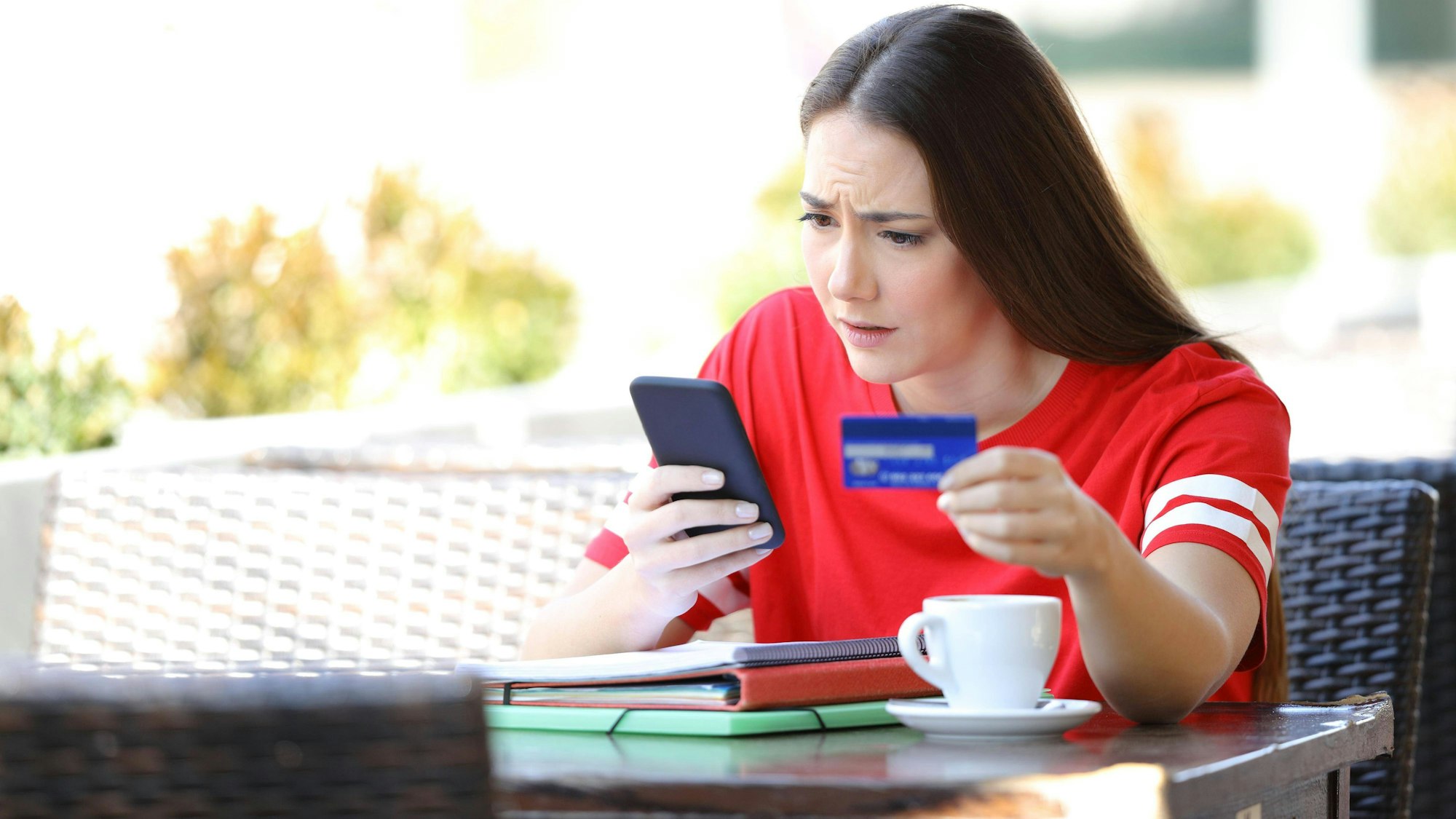 Eine Frau blickt auf ein Handy und hält eine Kreditkarte.