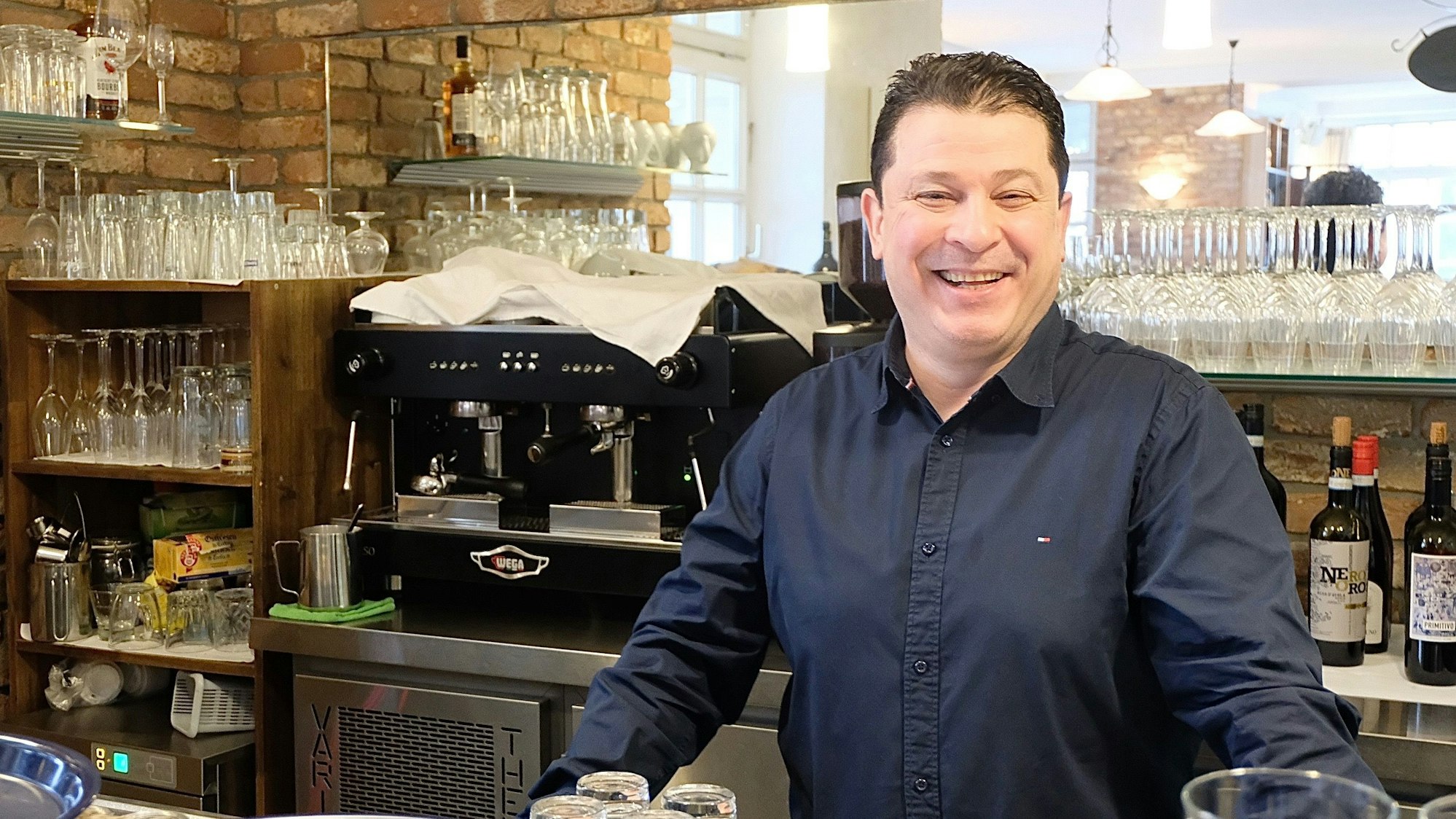 Der Wirt steht hinter dem Tresen.