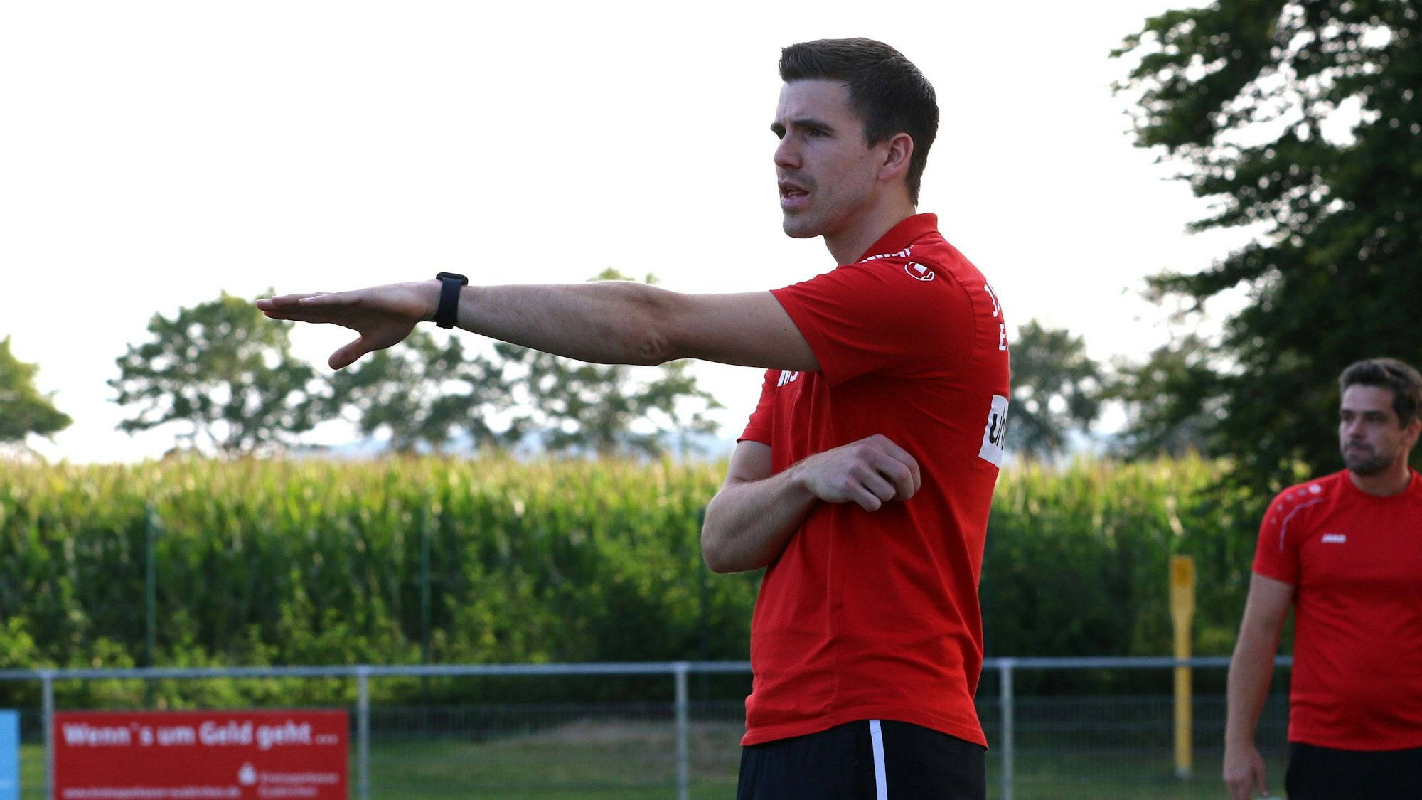 Das Bild zeigt Fußballtrainer Marcel Schmitz an der Seitenlinie. Er gibt mit einer Geste eine taktische Anweisung.