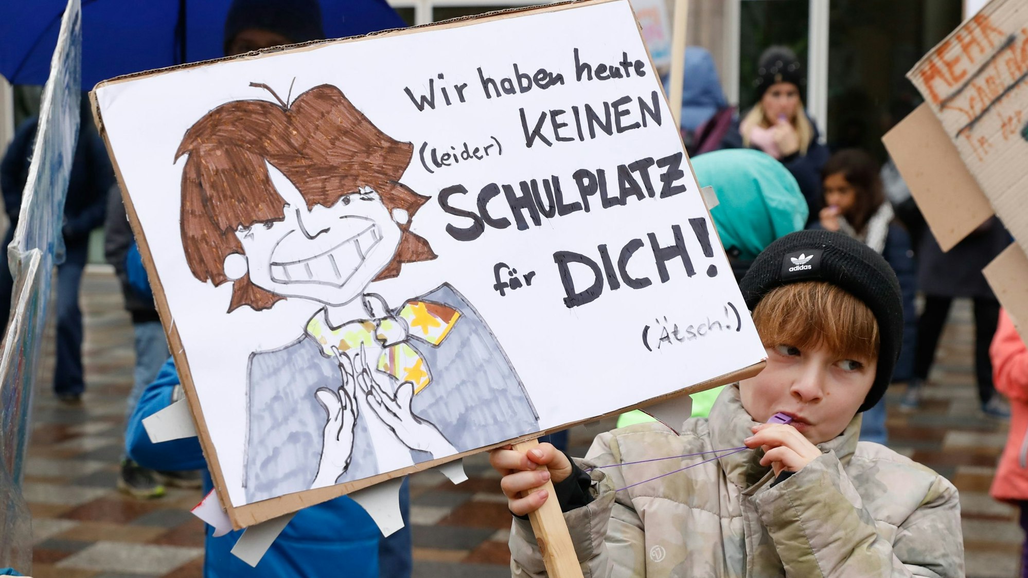 Ein Kind mit Trillerpfeife im Mund hält ein Schild hoch.
