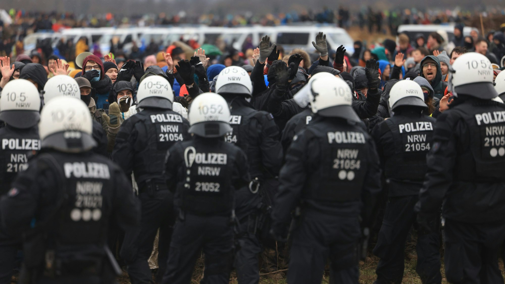 Polizisten und Demonstranten stehen sich bei der Demonstration von Klimaaktivisten am Rande des Braunkohletagebaus bei Lützerath gegenüber.