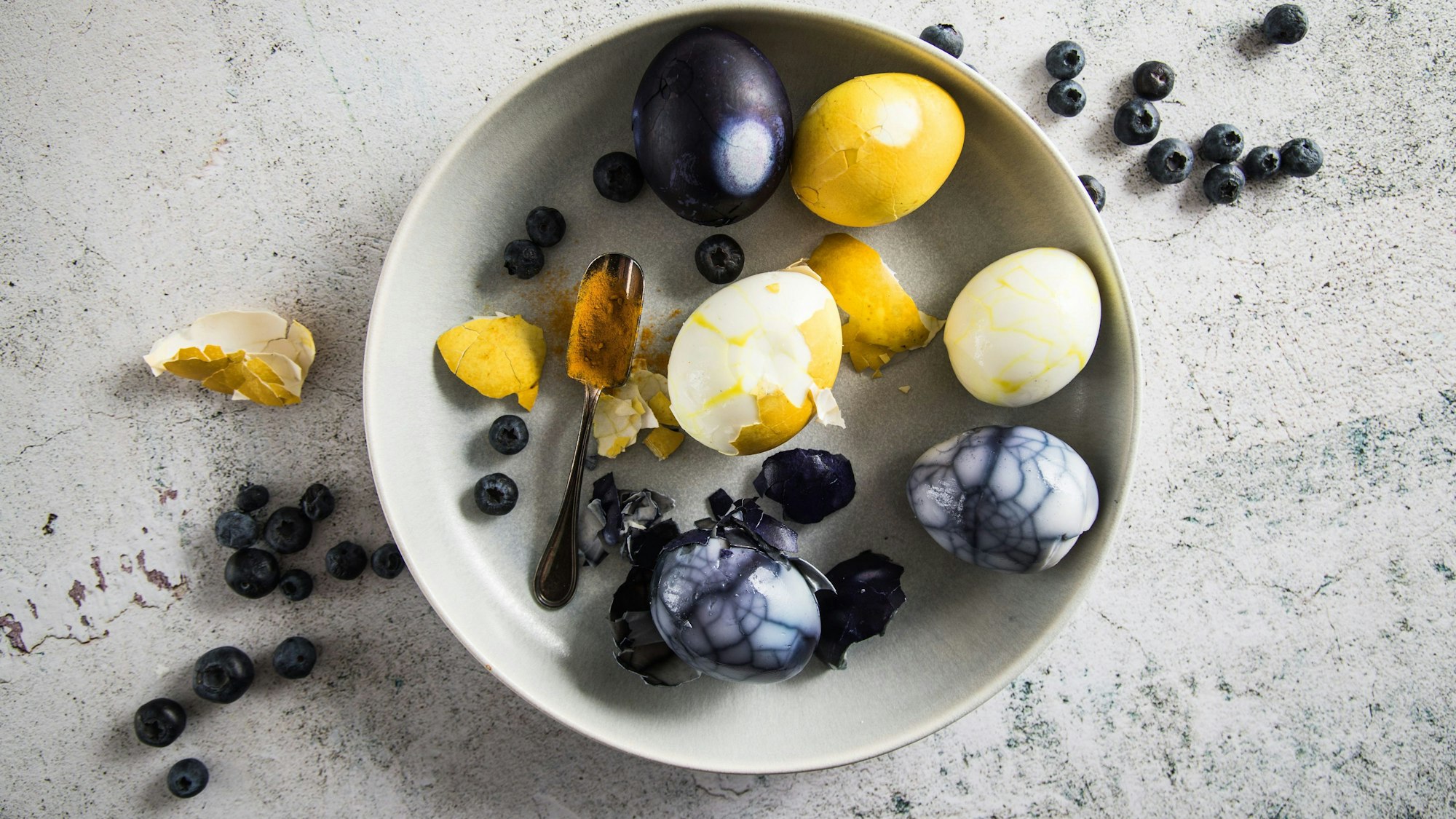 gelb und lila gefärbte Eier liegen in einer Schale