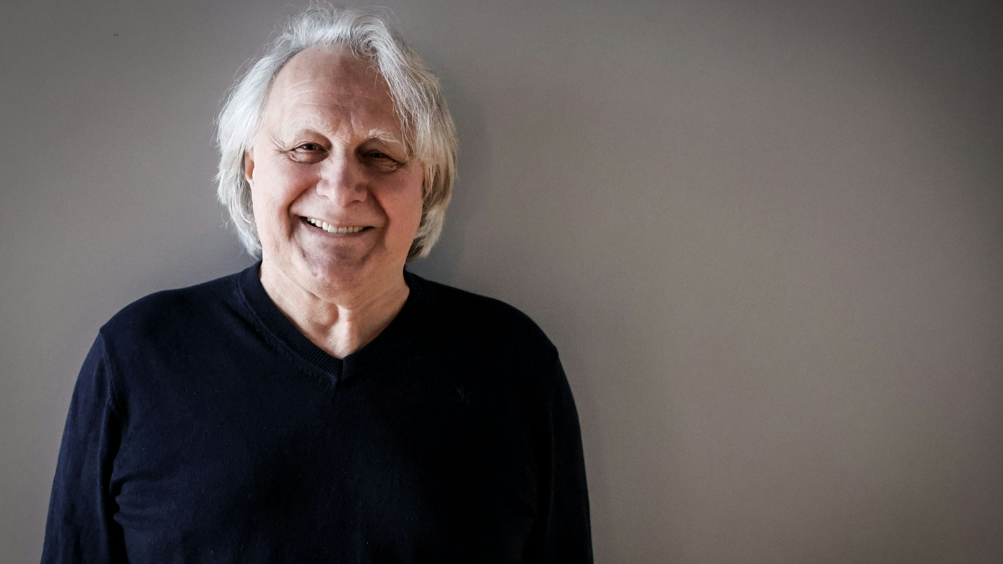 Peter Urban lächelt bei einem Fototermin in den Räumen des NDR.