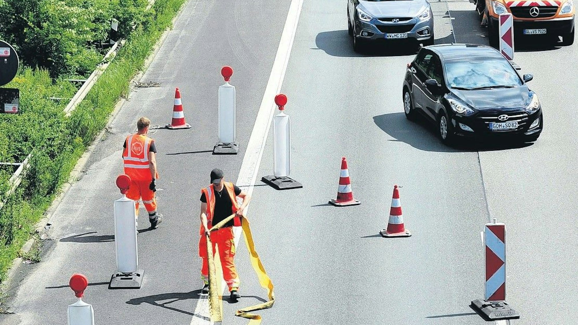 Ein Foto von einer früheren Baustelle: Arbeiter räumen Fahrbahnmarkierungen und Schilder ab.