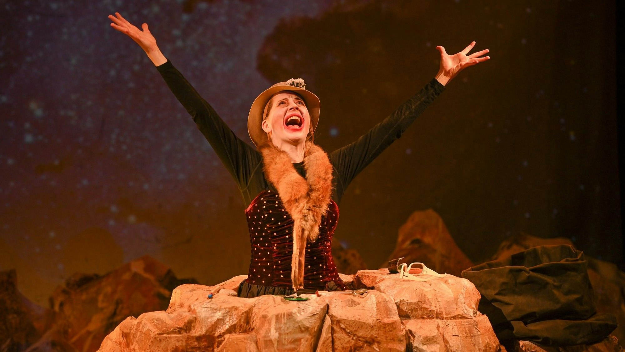 Hauptfigur Winnie steckt bis zur Hüfte in einem Stein fest und reckt die Arme schreiend nach oben.