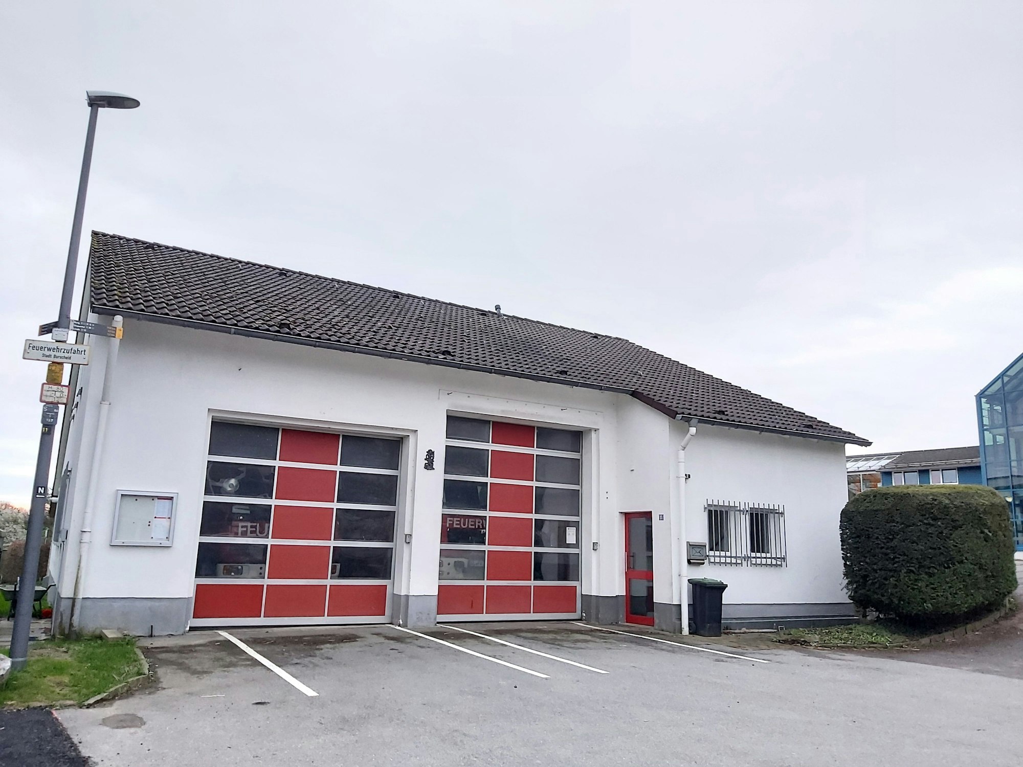 Eine kleine Feuerwache mit zwei teils durchsichtigen Garagentoren, hinter denen je ein Feuerwehrfahrzeug zu sehen ist.