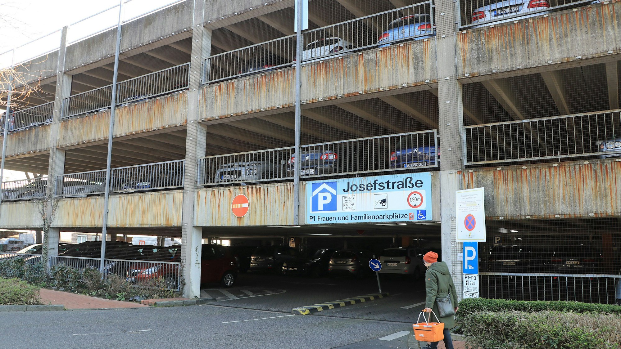 Das Bild zeigt das marode Parkhaus an der Josefstraße mit vielen parkenden Autos. Die Betonfassade ist an vielen Stellen von der Witterung braun gefärbt worden.