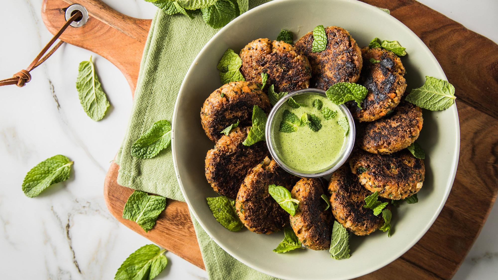 vegetarische Bratlinge mit grünem Dip angerichtet auf einem Teller