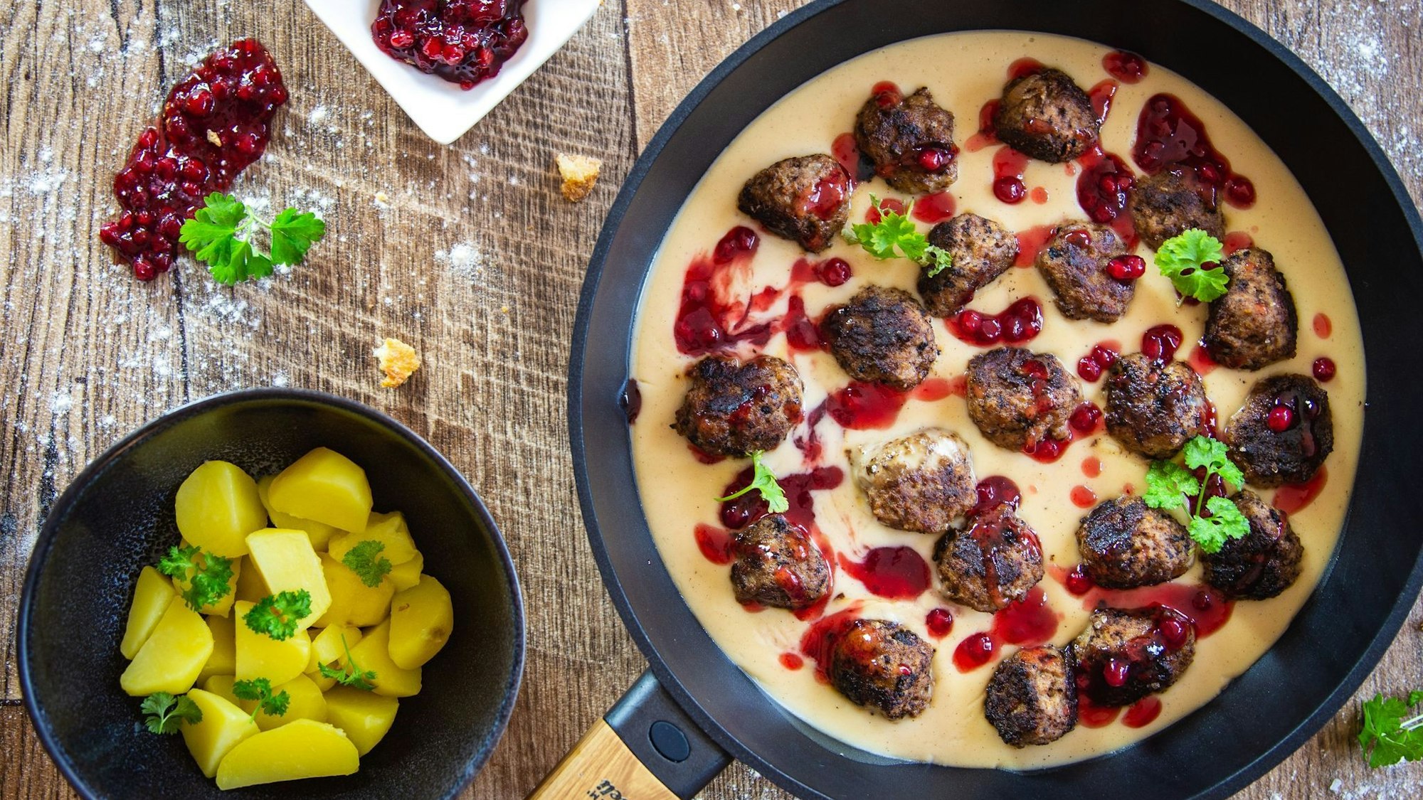 Schwedische Hackfleischbällchen, serviert in einer Rahmsoße, mit Kartoffeln als Beilage.