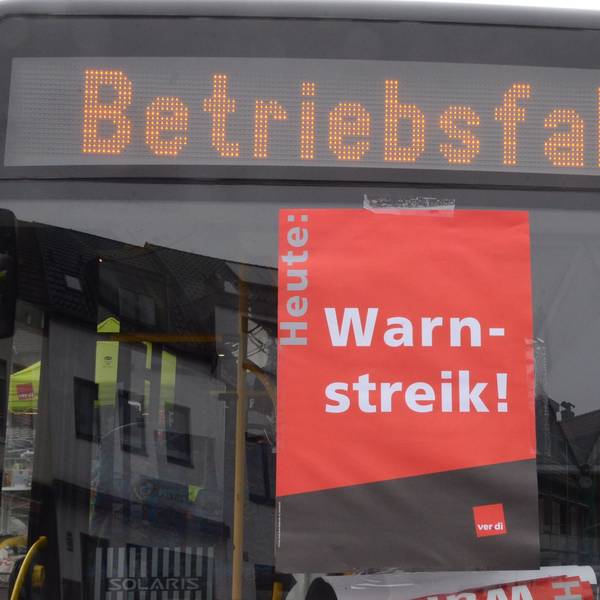 In einer Busscheibe klebt ein Plakat mit „Warnstreik“