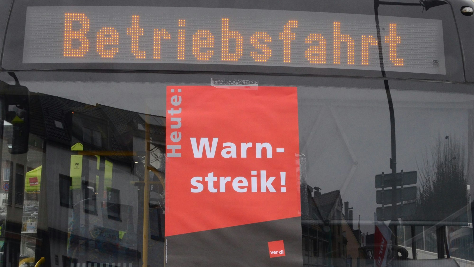 In einer Busscheibe klebt ein Plakat mit „Warnstreik“